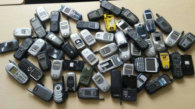 A large collection of old cell phones on a table.