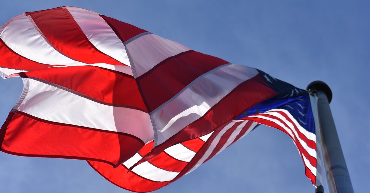 American flag waving against a clear blue sky.
