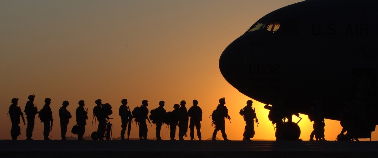 U.S. soldiers boarding a military aircraft at sunset.